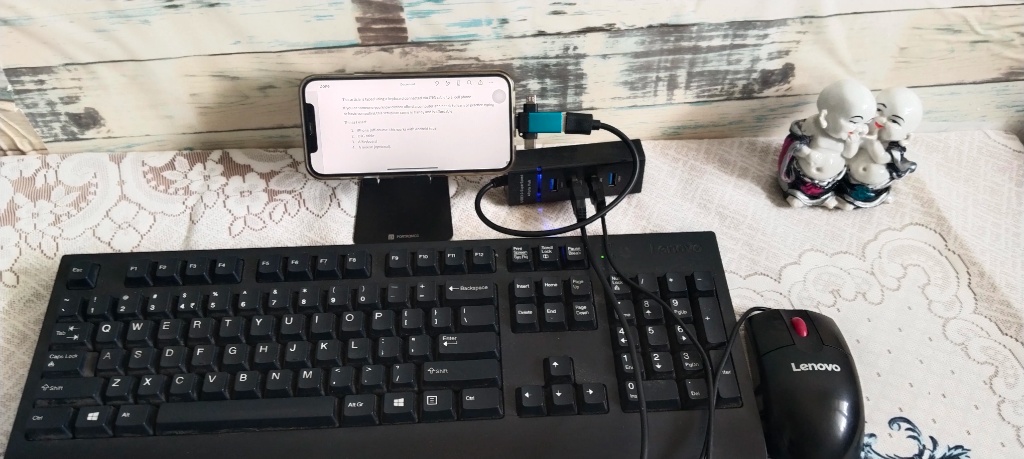 A smartphone on a stand connected to a full-size keyboard and mouse.